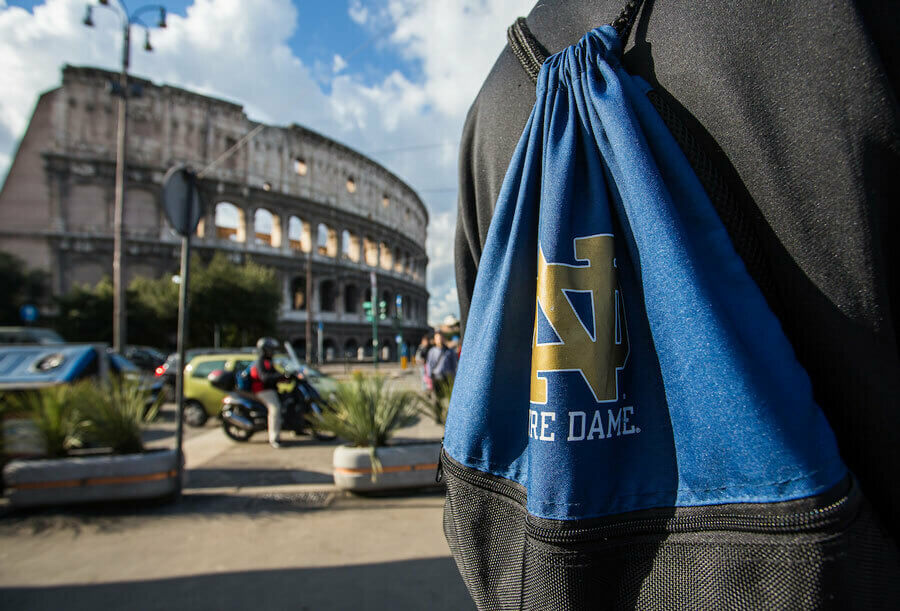 Close-up of a blue bag worn by a student in Rome. The Colosseum is in the background slightly out of focus.