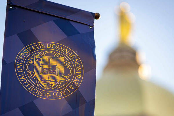 Close-up of a blue banner with the Notre Dame seal. The golden dome is out of focus in the background.