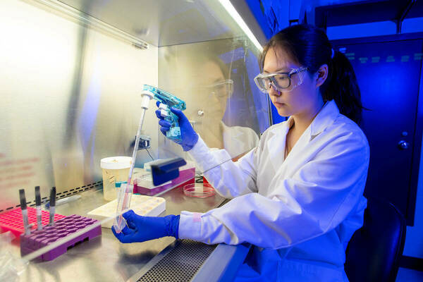 Woman in lab coat doing a chemistry experiment in a lab at Notre Dame